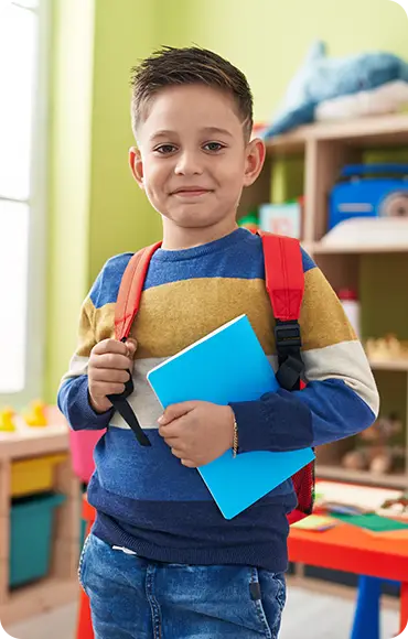 Junge mit Schulranzen und Heften im Klassenzimmer